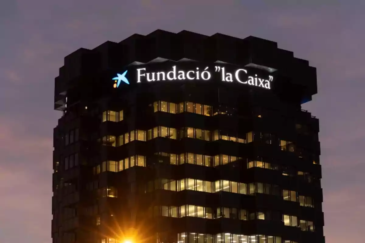 Edificio iluminado de noche con el letrero de "Fundació la Caixa" en la parte superior.