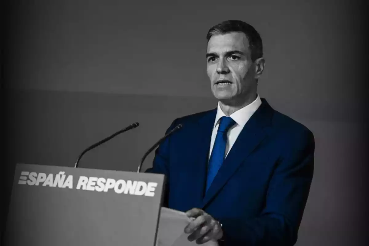 Hombre de traje azul hablando en un podio con el texto España Responde