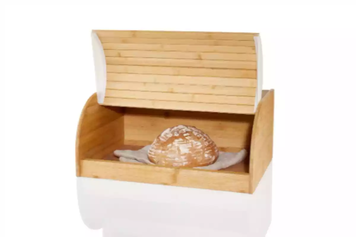 Panera de madera abierta con un pan redondo en su interior sobre un paño blanco Panera de madera abierta con un pan redondo en su interior sobre un paño blanco