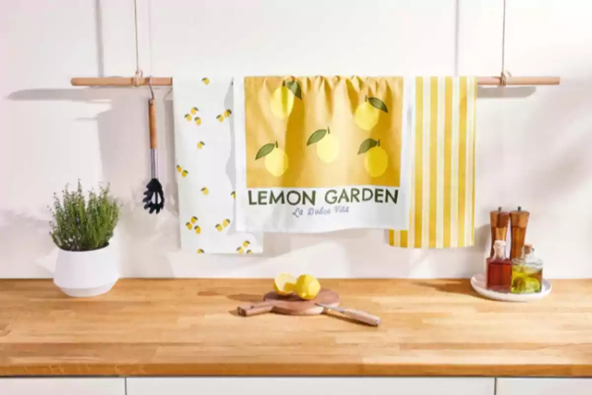Un estante de cocina con toallas decorativas de limones colgadas, una planta en maceta, utensilios de cocina y un tablero de madera con limones cortados. Un estante de cocina con toallas decorativas de limones colgadas, una planta en maceta, utensilios de cocina y un tablero de madera con limones cortados.