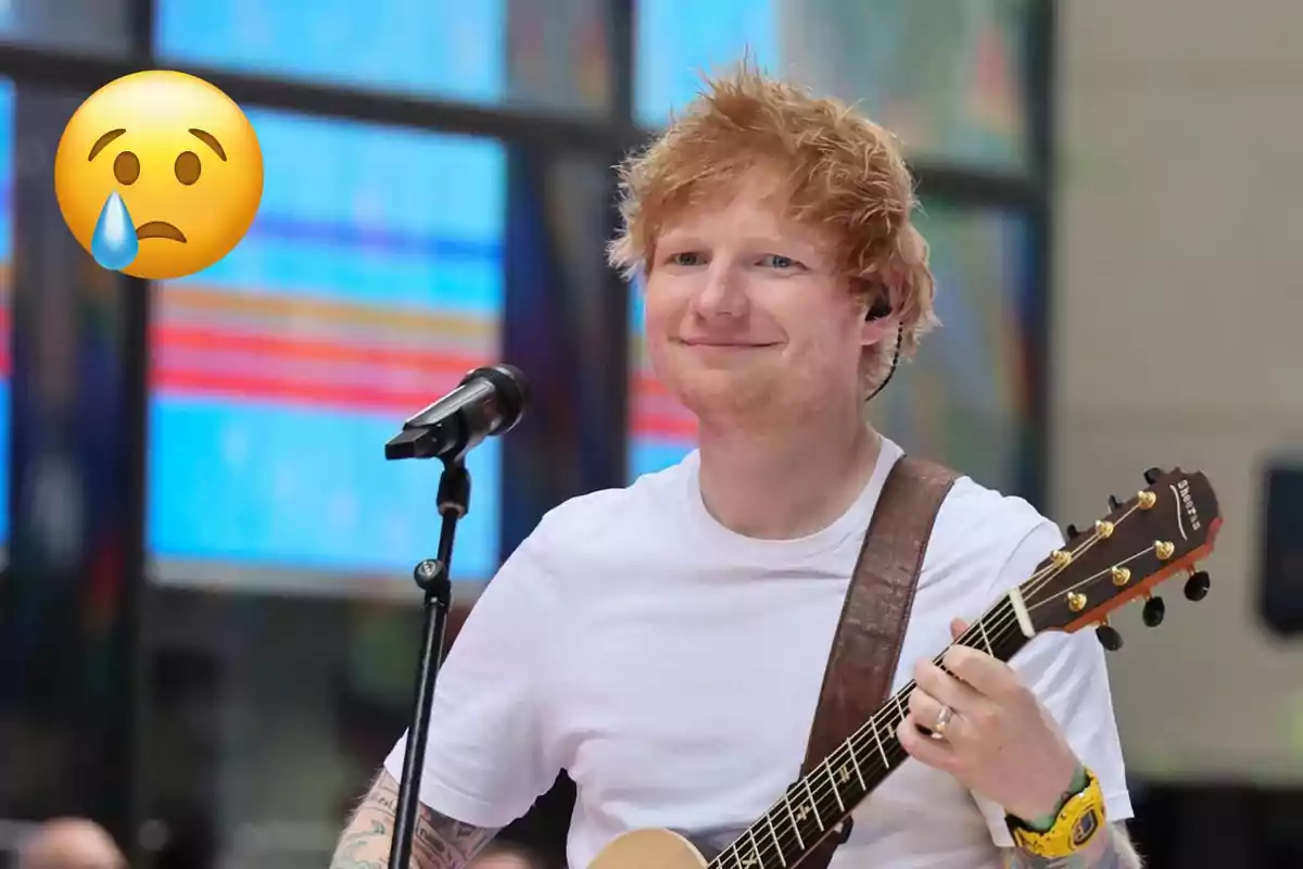 Persona con cabello rojo tocando una guitarra y sonriendo, con un micrófono frente a él y un emoji triste con una lágrima en la esquina superior izquierda.