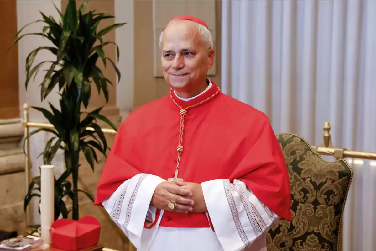 A man dressed in red and white ecclesiastical attire, standing in an elegant indoor setting with plants and curtains in the background. A man dressed in red and white ecclesiastical attire, standing in an elegant indoor setting with plants and curtains in the background.