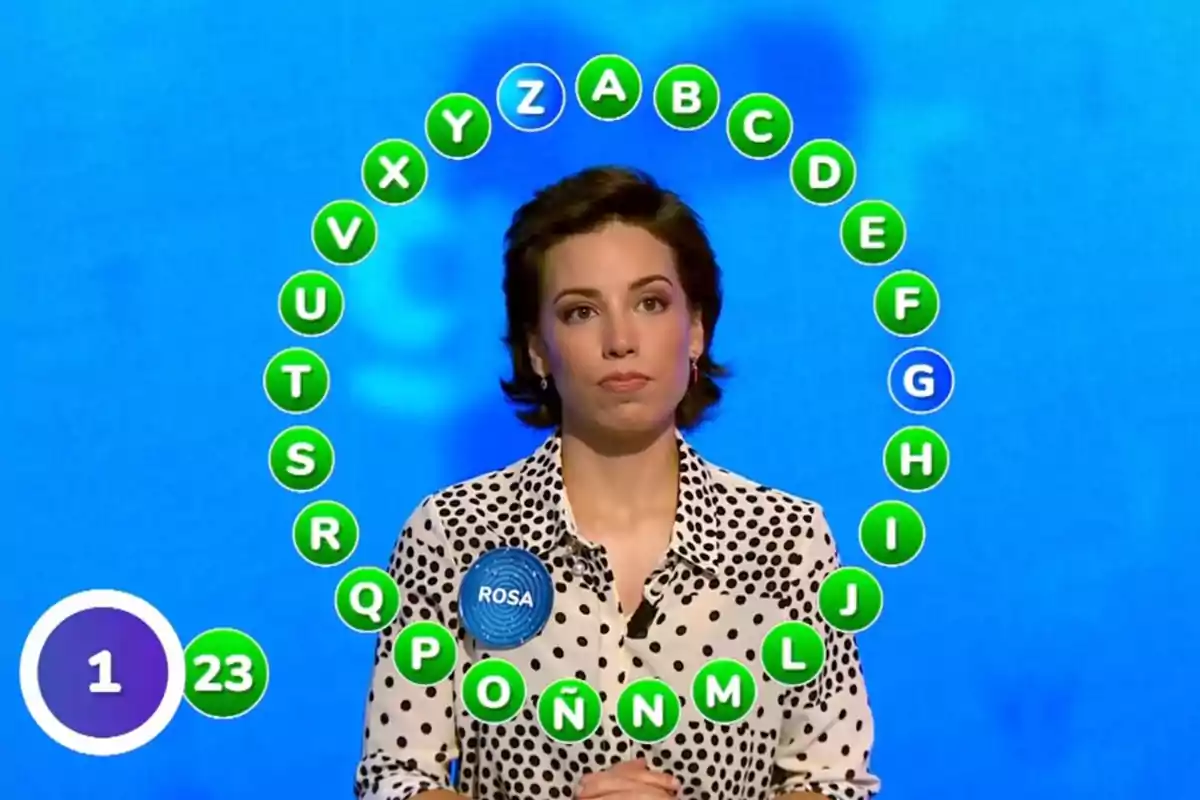 Rosa concursando en un programa de televisión con letras del abecedario en círculo a su alrededor y un fondo azul. Captura de 'Pasapalabra' Rosa concursando en un programa de televisión con letras del abecedario en círculo a su alrededor y un fondo azul. Captura de 'Pasapalabra'