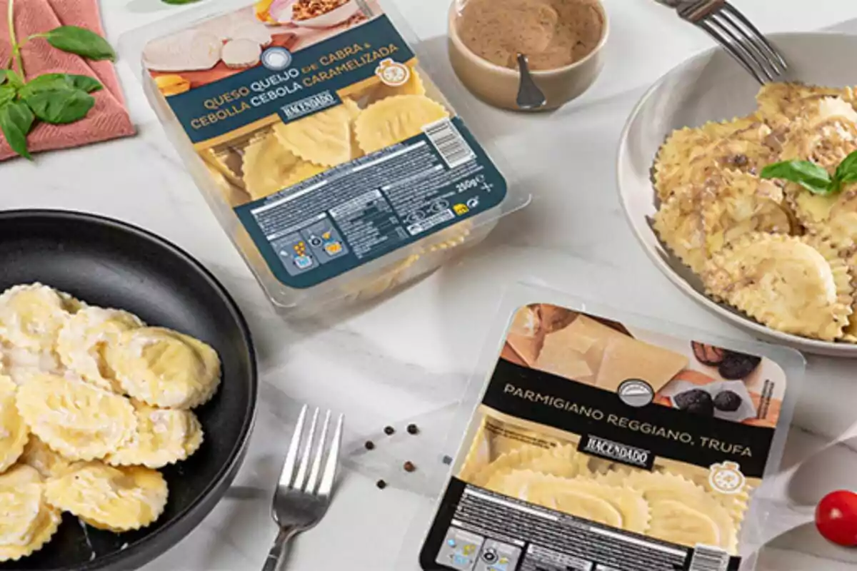 Una mesa con platos de pasta rellena y envases de raviolis de diferentes sabores, acompañados de una salsa y decoraciones de albahaca.