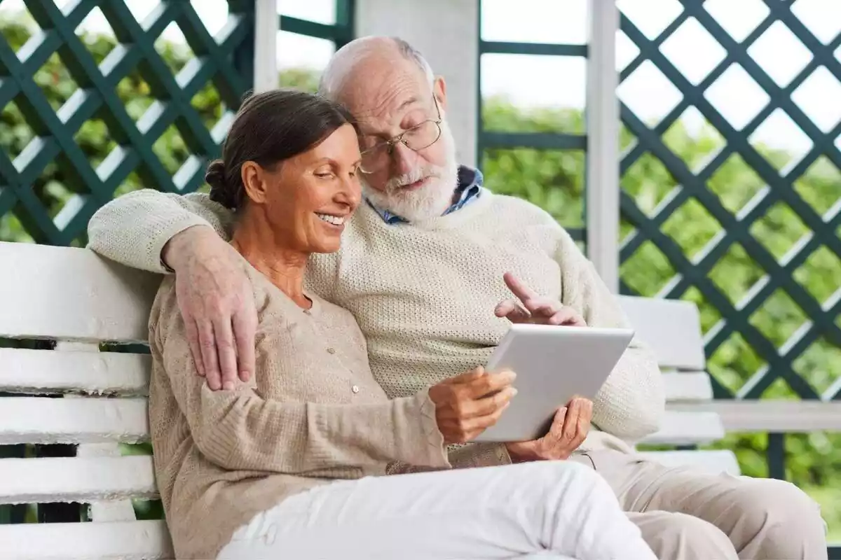 Pareja mayor, dos pensionistas, consultando datos en una tablet