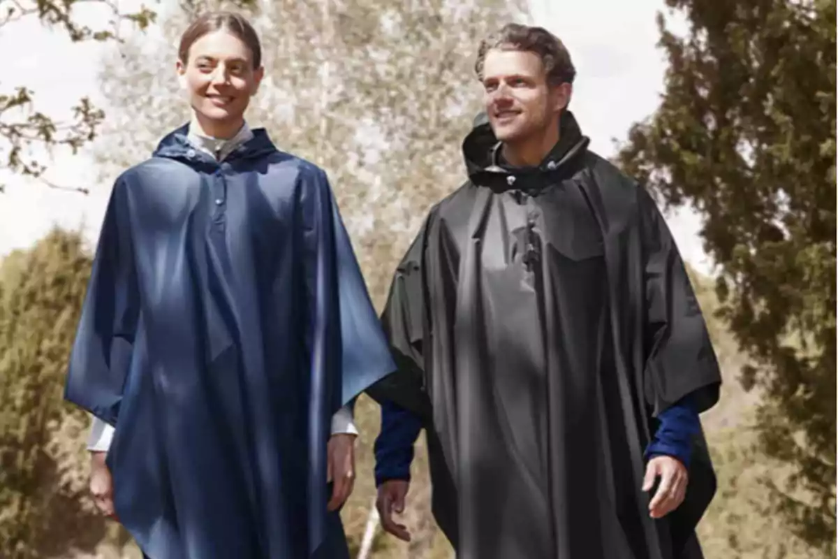 Dos personas caminando al aire libre con ponchos impermeables, una en azul y otra en negro, rodeadas de árboles. Dos personas caminando al aire libre con ponchos impermeables, una en azul y otra en negro, rodeadas de árboles.
