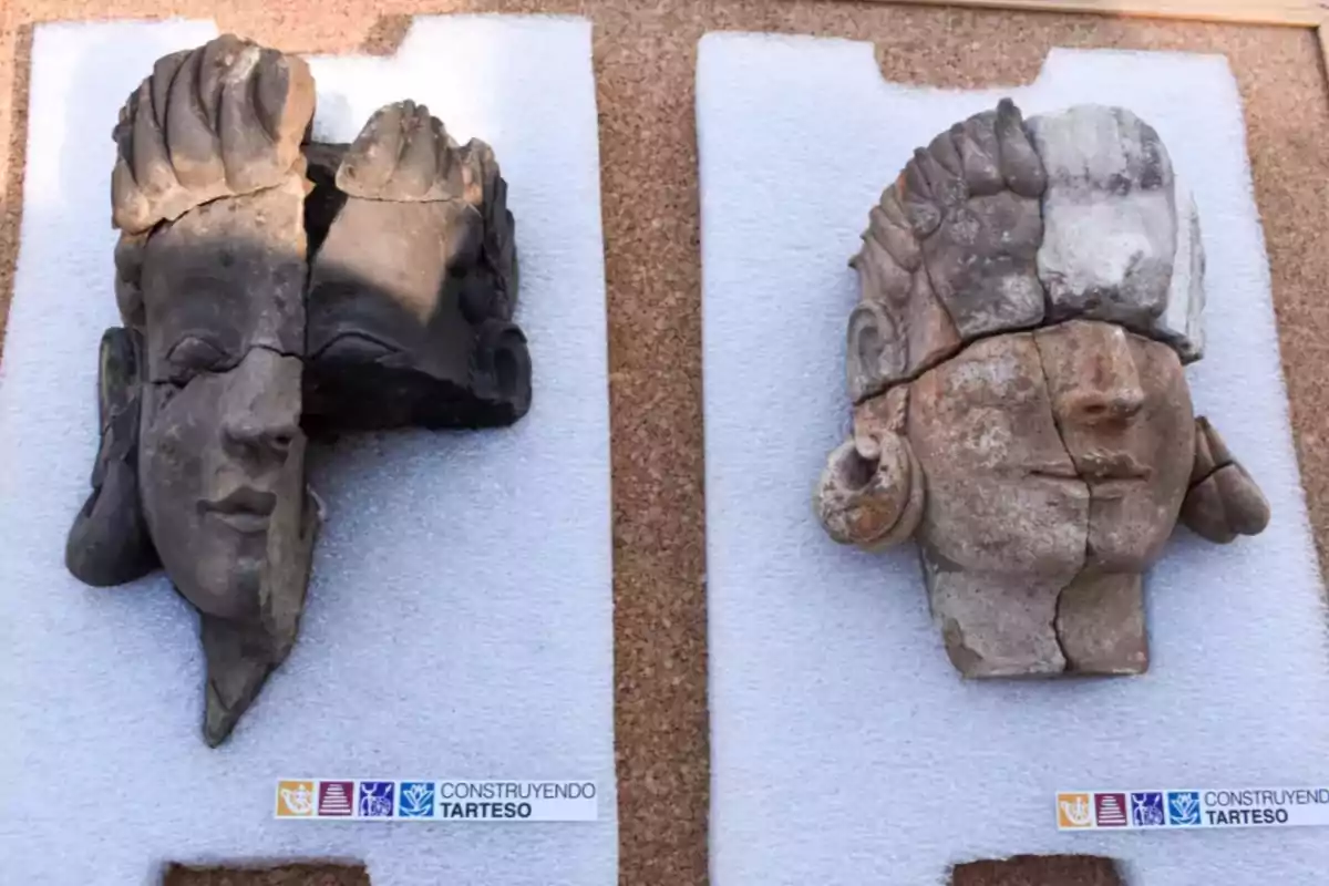 Dos esculturas de cabezas antiguas fragmentadas sobre una superficie blanca, con un logotipo que dice Dos esculturas de cabezas antiguas fragmentadas sobre una superficie blanca, con un logotipo que dice