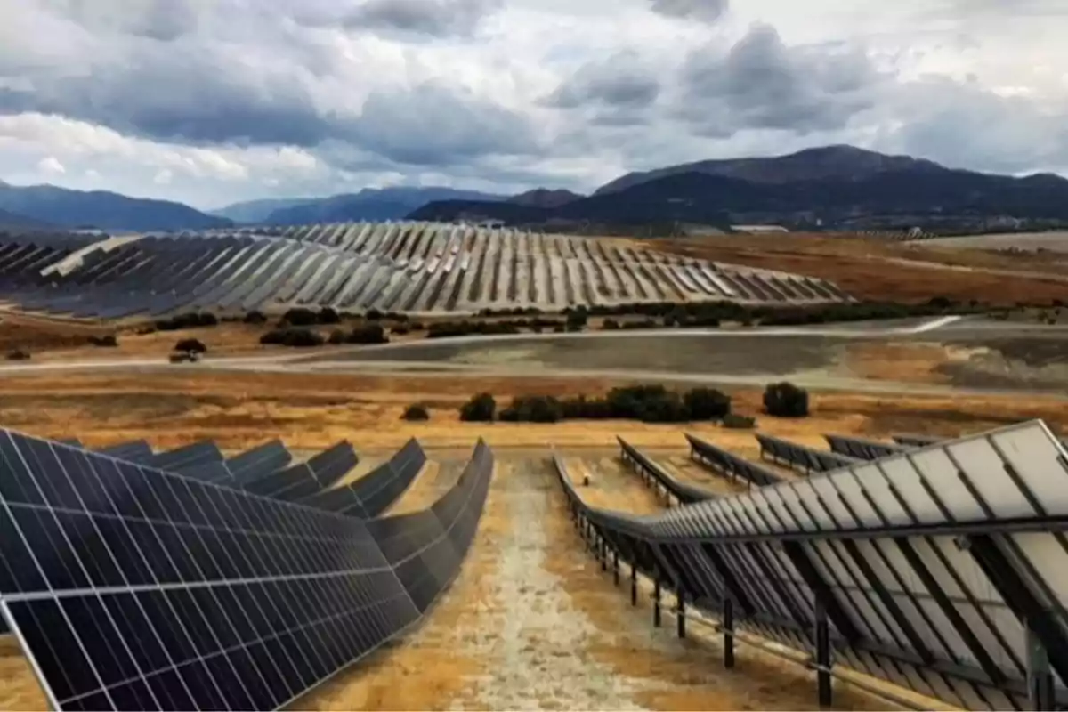 Parque solar con paneles fotovoltaicos en un paisaje montañoso bajo un cielo nublado. Parque solar con paneles fotovoltaicos en un paisaje montañoso bajo un cielo nublado.