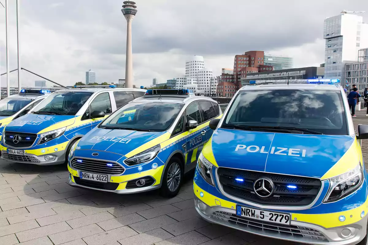 Vehículos policiales estacionados en una calle con un edificio alto y moderno al fondo. Vehículos policiales estacionados en una calle con un edificio alto y moderno al fondo.
