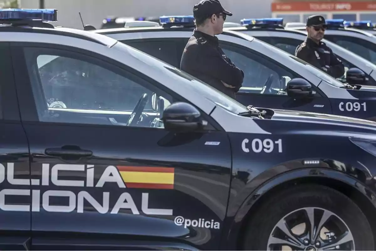 Policías nacionales de pie junto a sus vehículos patrulla.