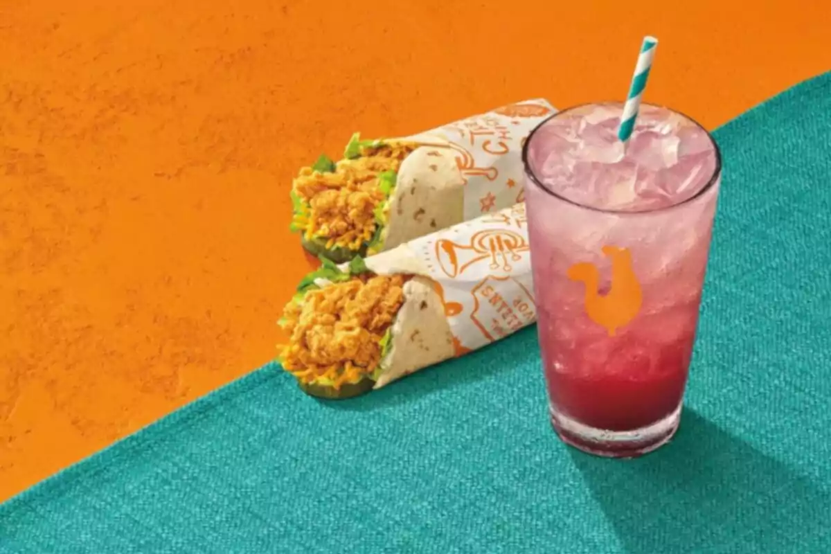 Dos burritos de pollo empanizado con lechuga y queso acompañados de una bebida rosada con hielo y popote sobre una mesa azul y fondo naranja Dos burritos de pollo empanizado con lechuga y queso acompañados de una bebida rosada con hielo y popote sobre una mesa azul y fondo naranja