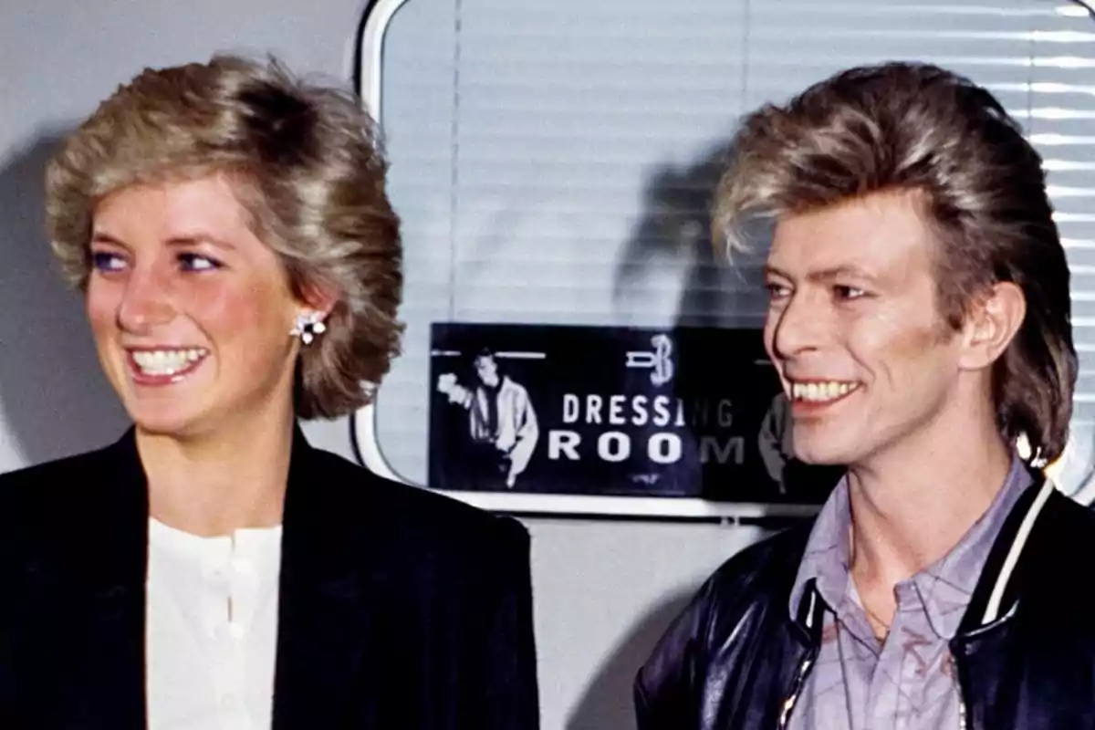 Lady Di and David Bowie smiling pose in front of a sign that says Lady Di and David Bowie smiling pose in front of a sign that says
