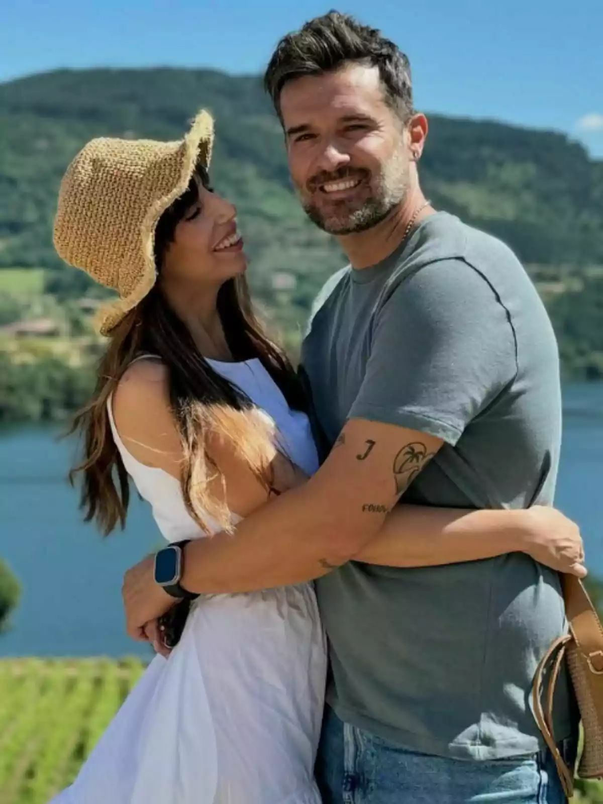 Almudena Cid y Gerardo Berodia sonriente se abraza al aire libre con un paisaje montañoso y un lago de fondo. Almudena Cid y Gerardo Berodia sonriente se abraza al aire libre con un paisaje montañoso y un lago de fondo.