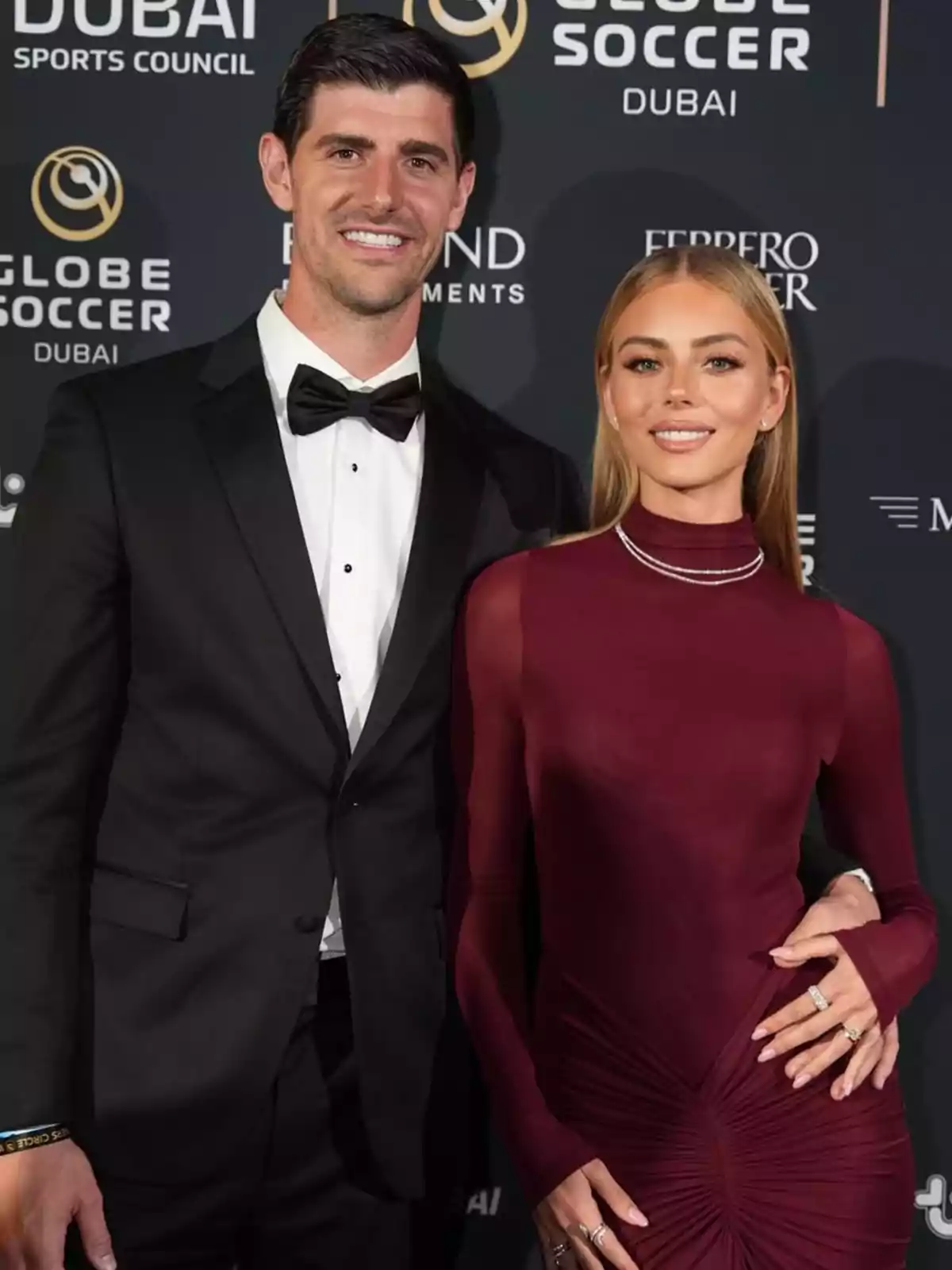Thibaut Courtois y Mishel Gerzig elegantemente vestida posa en un evento de gala con un fondo de logotipos de Globe Soccer en Dubai. Thibaut Courtois y Mishel Gerzig elegantemente vestida posa en un evento de gala con un fondo de logotipos de Globe Soccer en Dubai.