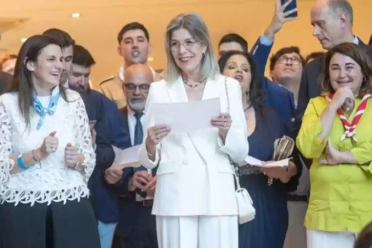 A group of people smiles and holds papers at a social event. A group of people smiles and holds papers at a social event.