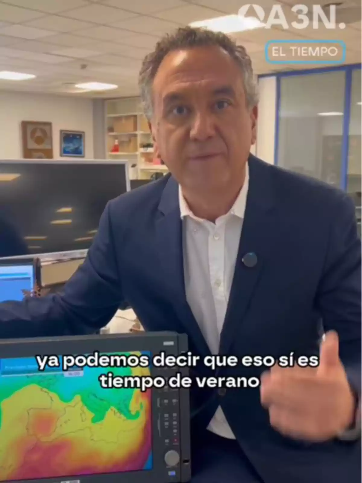 Un hombre en una oficina señala una pantalla que muestra un mapa meteorológico con colores cálidos y el texto Un hombre en una oficina señala una pantalla que muestra un mapa meteorológico con colores cálidos y el texto