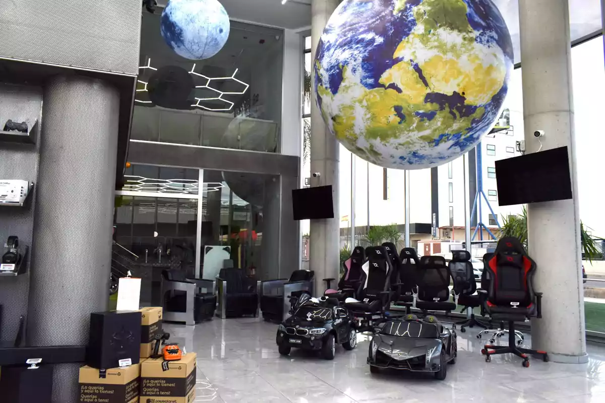 A modern space with gaming chairs, toy cars and hanging planet decorations from the ceiling.