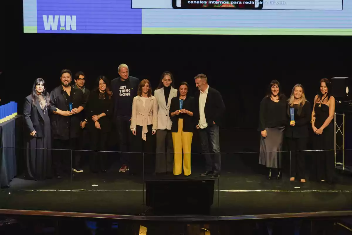 Un grupo de personas posando en un escenario durante un evento de premiación.