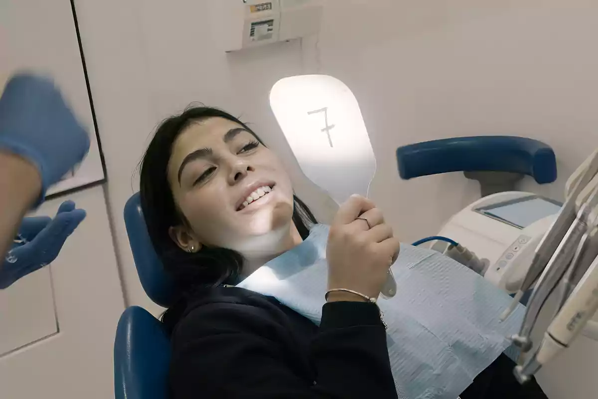 A person in a dentist's chair holding a mirror with the number seven reflected.