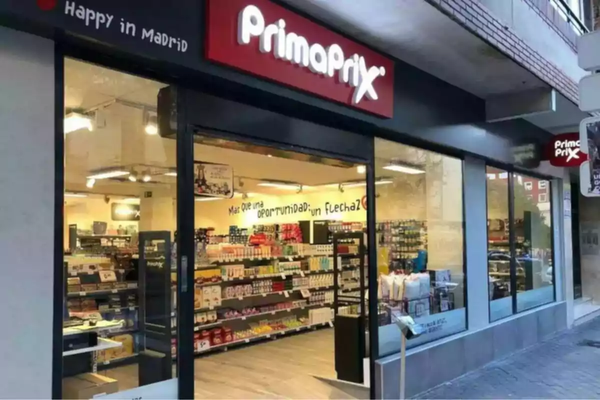 Fachada de una tienda PrimaPrix en Madrid con productos visibles a través de las ventanas.