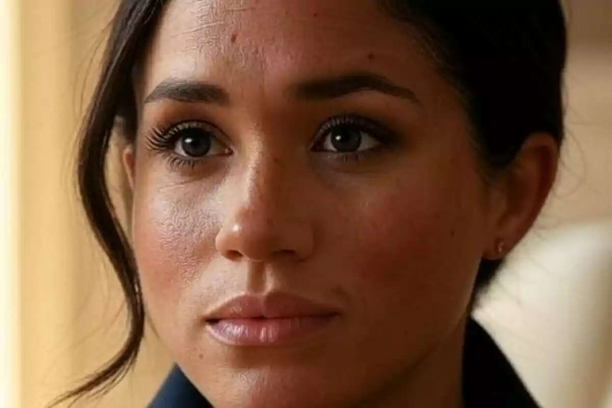Primer plano de Meghan Markle con expresión seria y cabello oscuro recogido Primer plano de Meghan Markle con expresión seria y cabello oscuro recogido