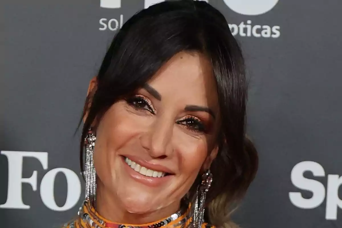 Nagore Robles sonriente con cabello oscuro y aretes largos posando frente a un fondo con logotipos. Nagore Robles sonriente con cabello oscuro y aretes largos posando frente a un fondo con logotipos.