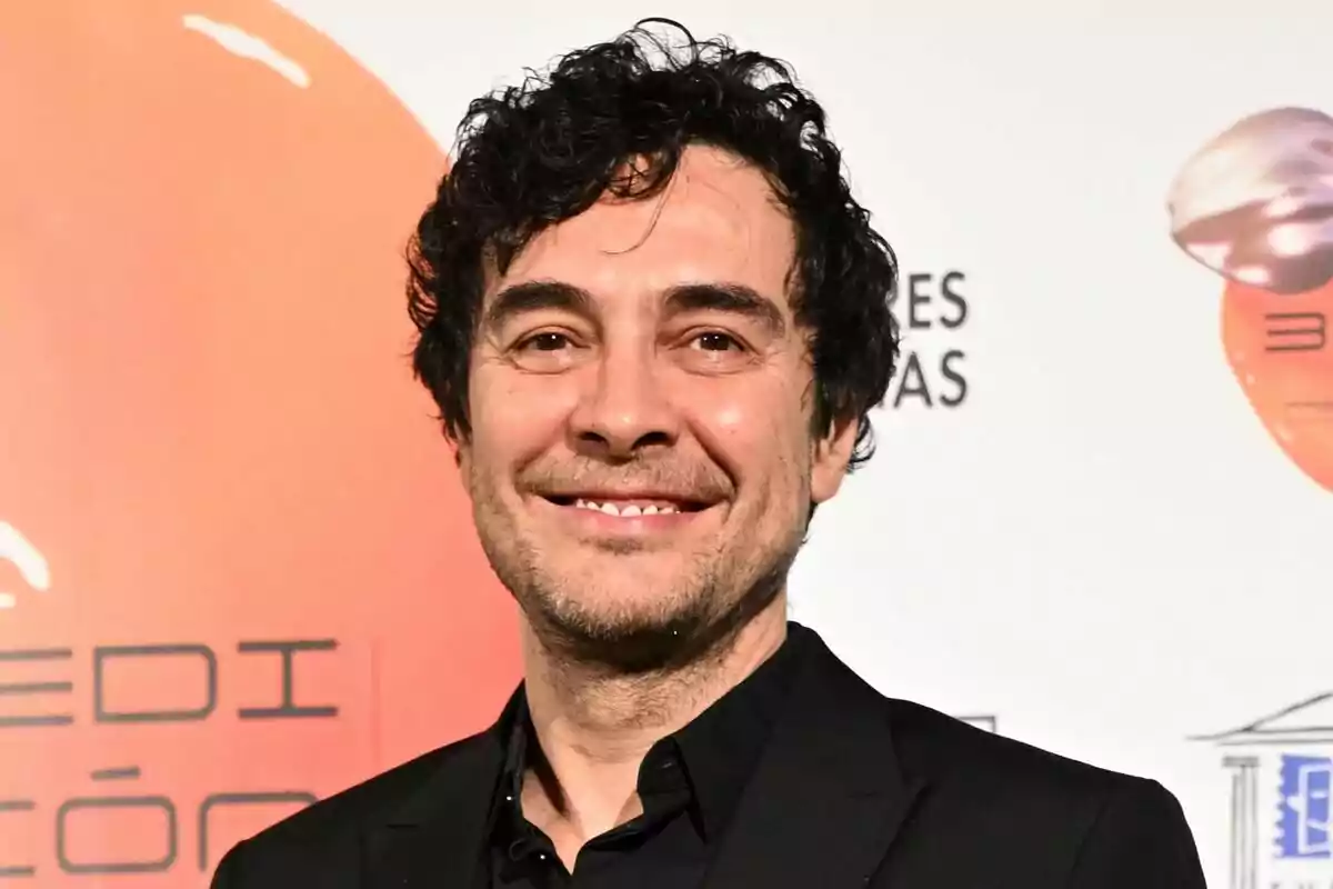 José Manuel Seda sonriente con cabello rizado y barba ligera en un evento con fondo de logotipos.