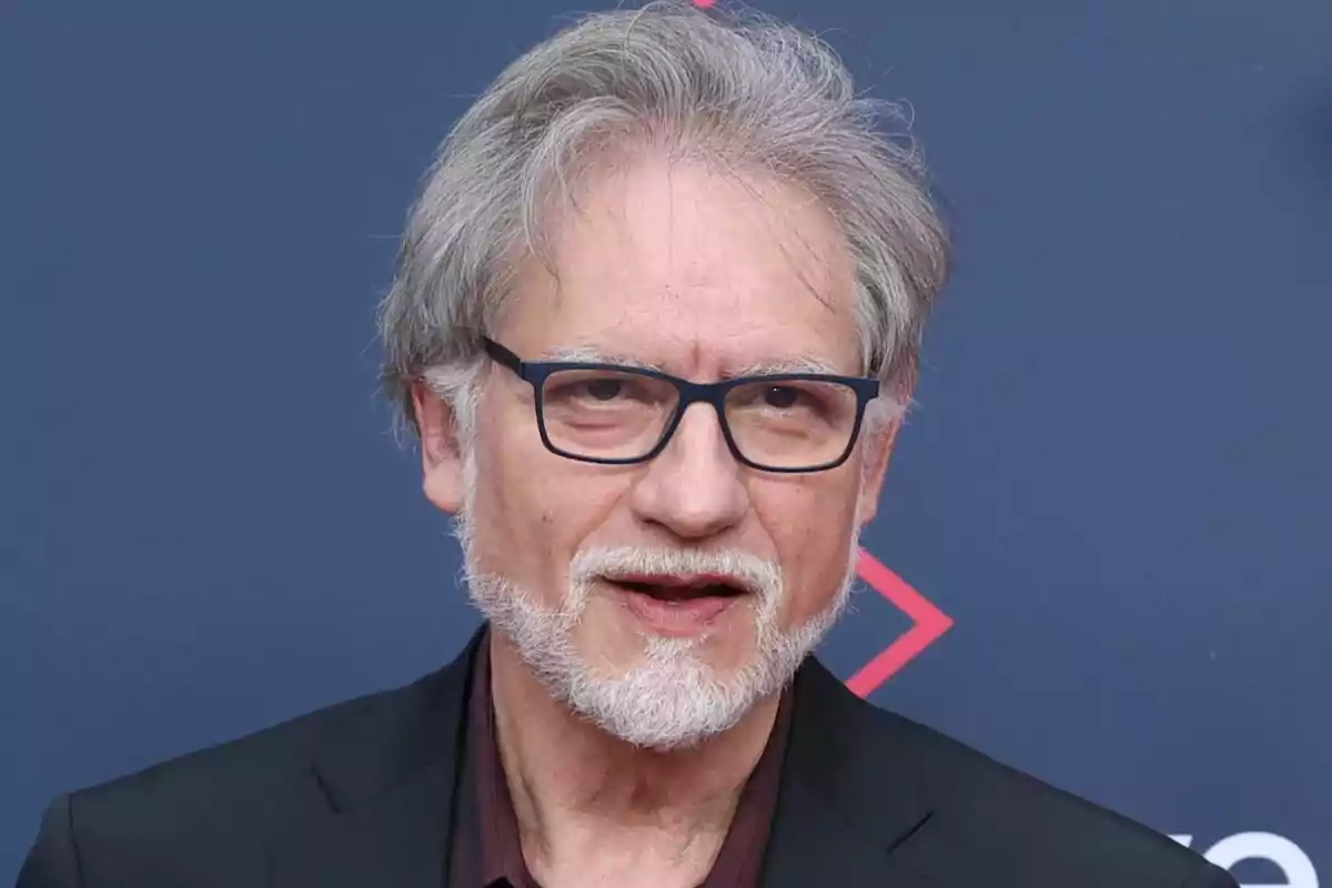 Nancho Novo con gafas y barba blanca frente a un fondo azul.