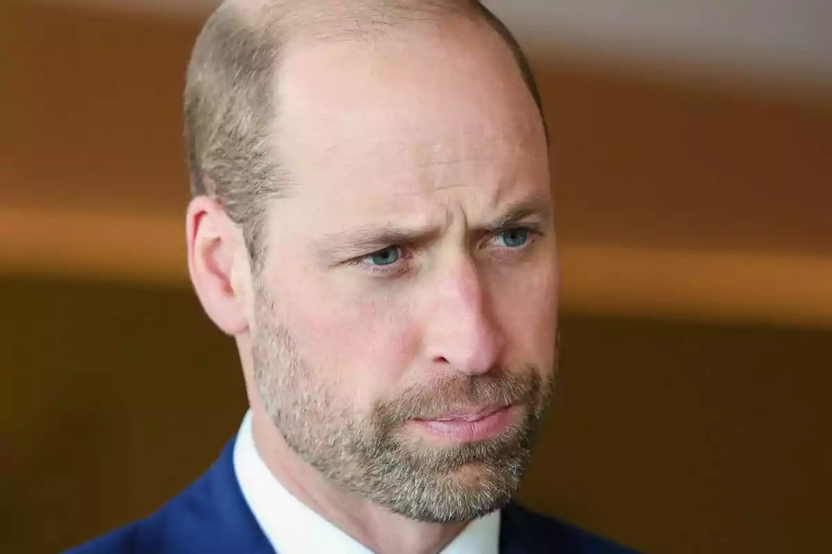 Primer plano del príncipe Guillermo con rostro serio y traje azul