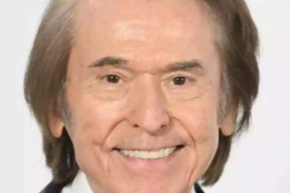 Primer plano de Raphael con cabello castaño claro y sonrisa amplia.
