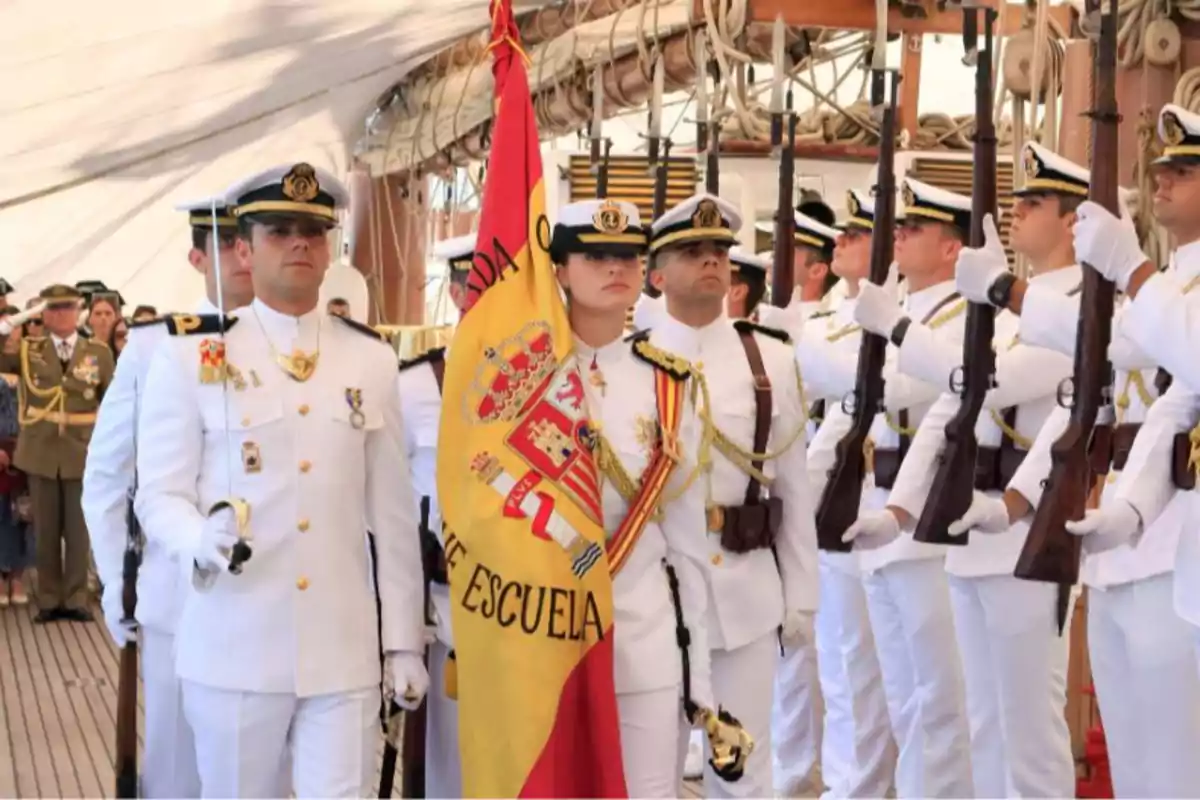 Group of naval officers in white uniforms holding a flag and rifles during a ceremony on a ship. Group of naval officers in white uniforms holding a flag and rifles during a ceremony on a ship.