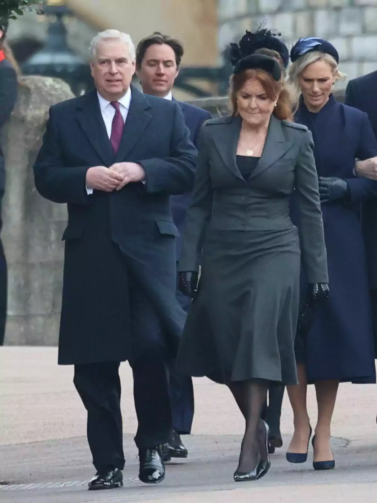 Un grupo de personas vestidas formalmente camina por una calle, con el príncipe Andrés de cabello canoso y Sarah Ferguson de cabello rojizo al frente. Un grupo de personas vestidas formalmente camina por una calle, con el príncipe Andrés de cabello canoso y Sarah Ferguson de cabello rojizo al frente.