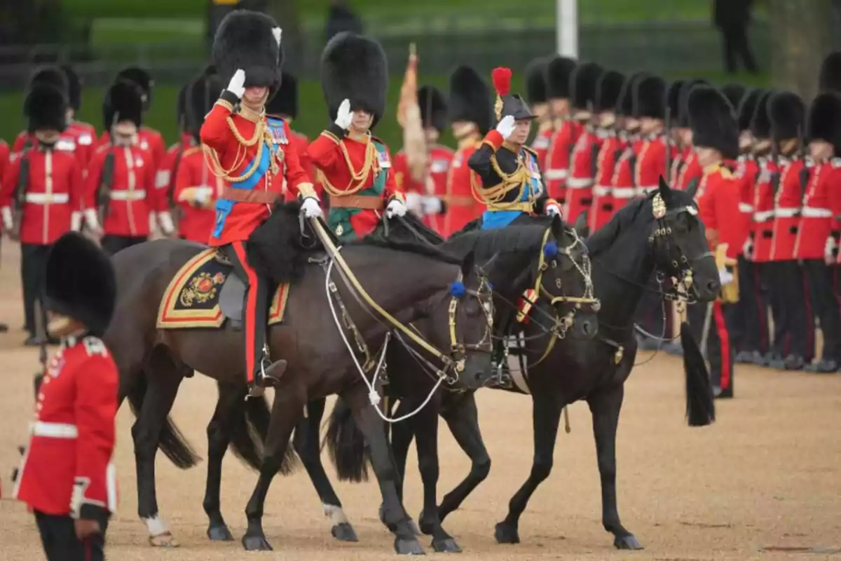 Desfile militar con soldados británicos uniformados montando caballos y saludando mientras otros soldados marchan en formación al fondo Desfile militar con soldados británicos uniformados montando caballos y saludando mientras otros soldados marchan en formación al fondo