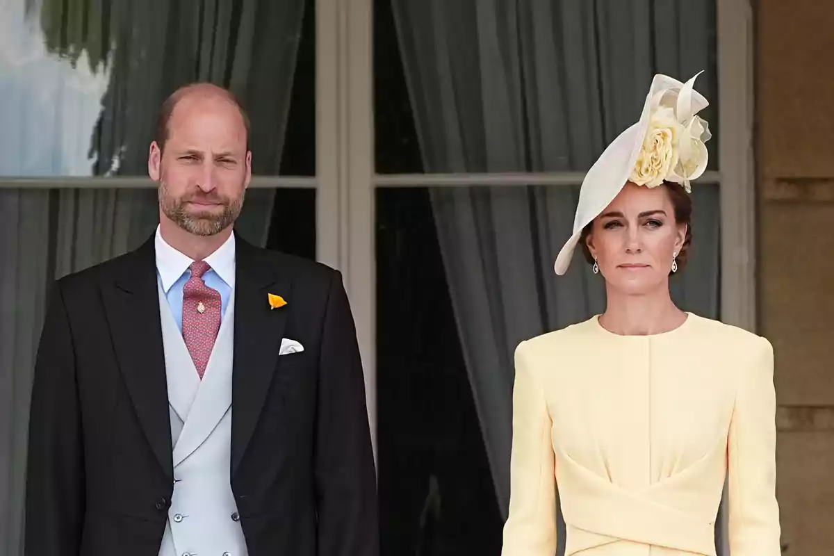 El príncipe Guillermo y Kate Middleton elegantemente vestida de pie frente a una ventana con cortinas. El príncipe Guillermo y Kate Middleton elegantemente vestida de pie frente a una ventana con cortinas.