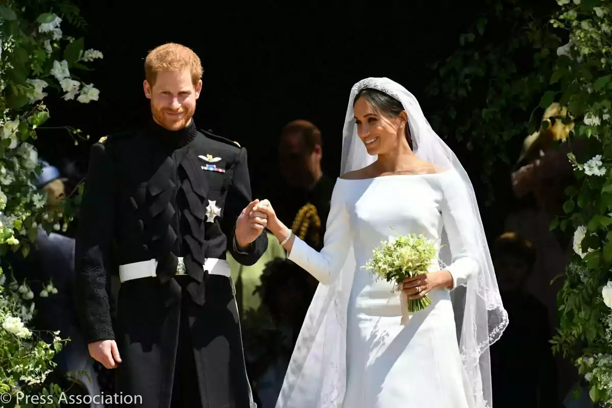 Prince Harry and Meghan Markle smiling in wedding dress leave a building decorated with flowers. Prince Harry and Meghan Markle smiling in wedding dress leave a building decorated with flowers.
