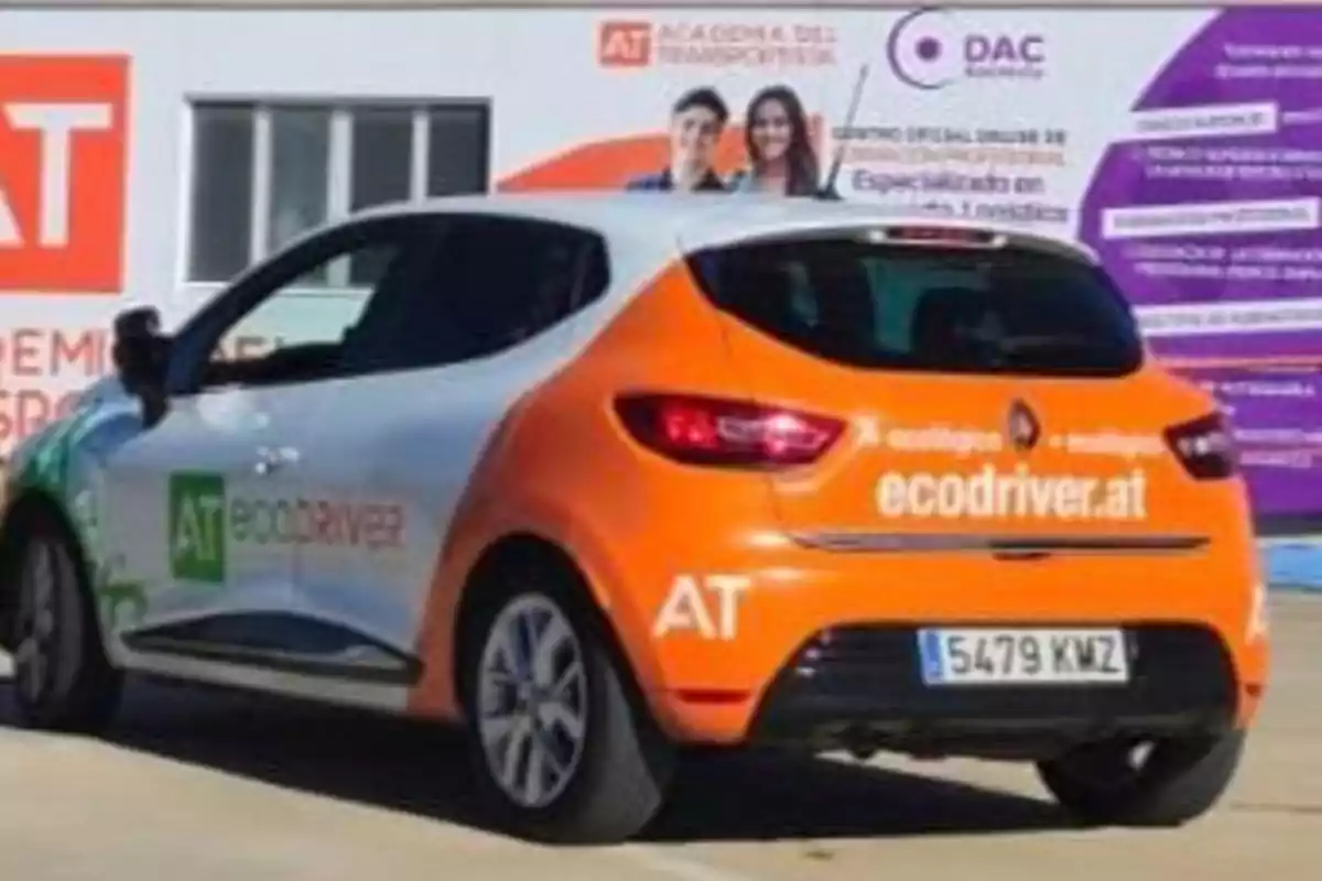 Un coche con la marca "ecodriver.at" y matrícula "5479 KMZ" está estacionado frente a un edificio con carteles de la "Academia del Transportista".