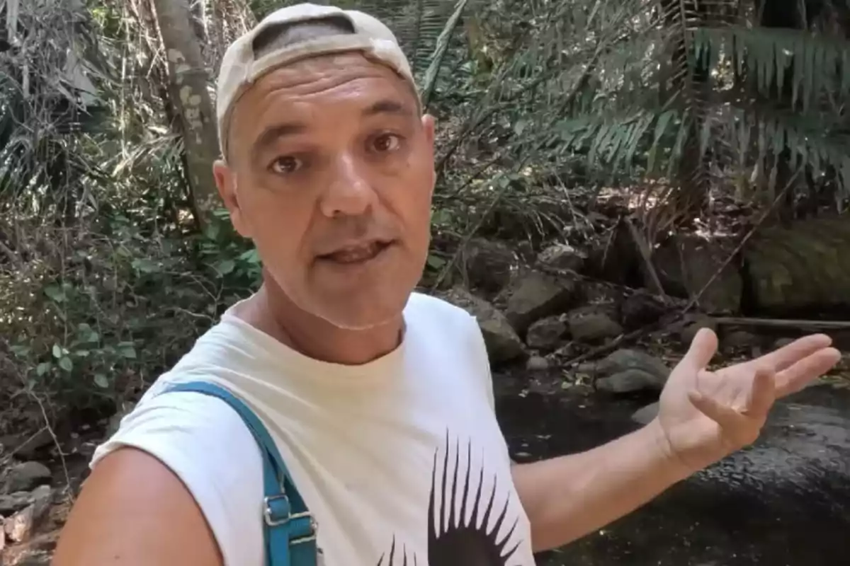 Persona con gorra y camiseta blanca en un entorno de selva o bosque tropical.