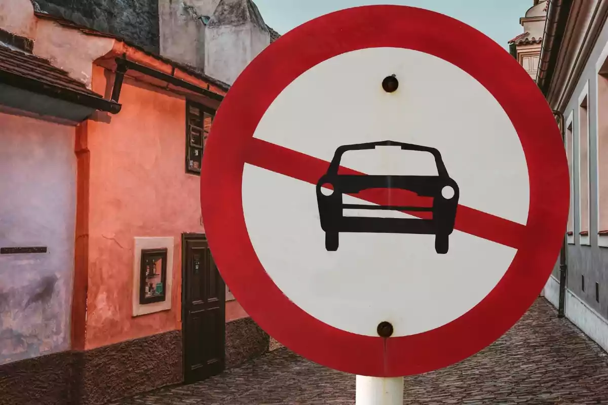 Señal de tráfico de prohibido el paso de vehículos en una calle estrecha con edificios antiguos de fondo.