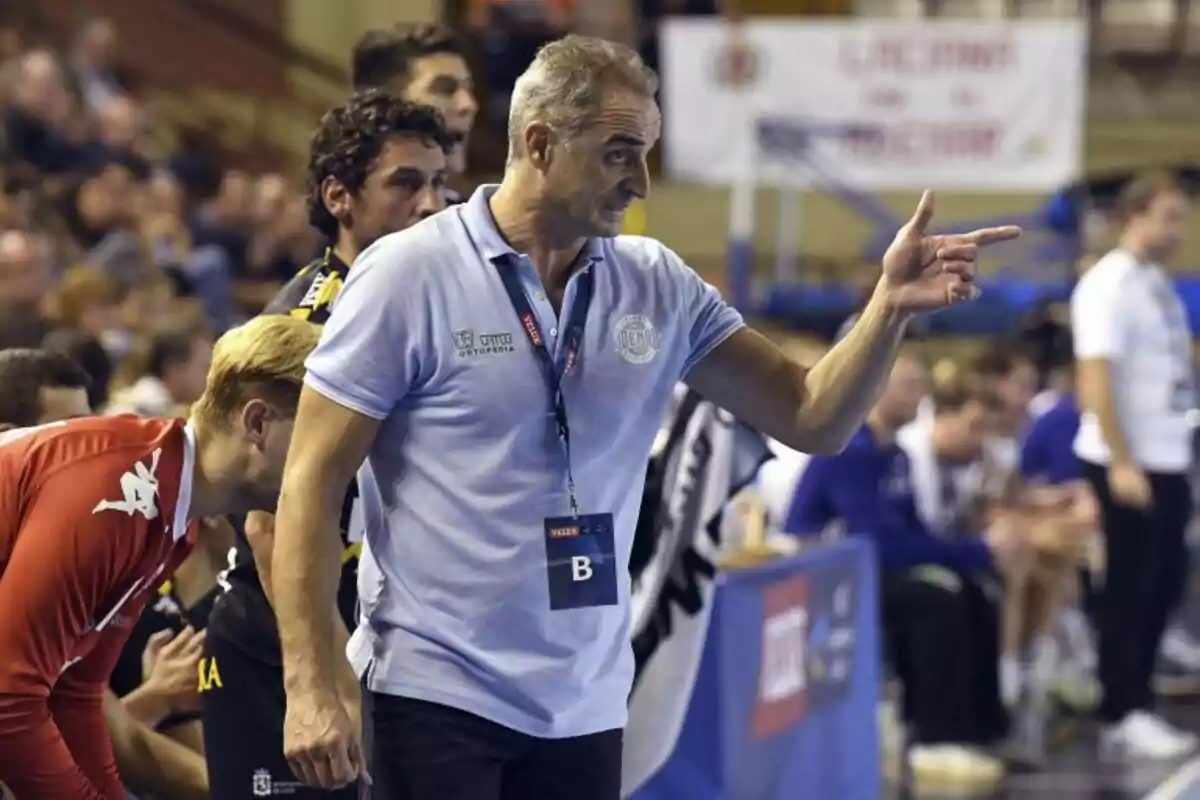 Entrenador de balonmano dando indicaciones a sus jugadores durante un partido en un estadio lleno de espectadores Entrenador de balonmano dando indicaciones a sus jugadores durante un partido en un estadio lleno de espectadores