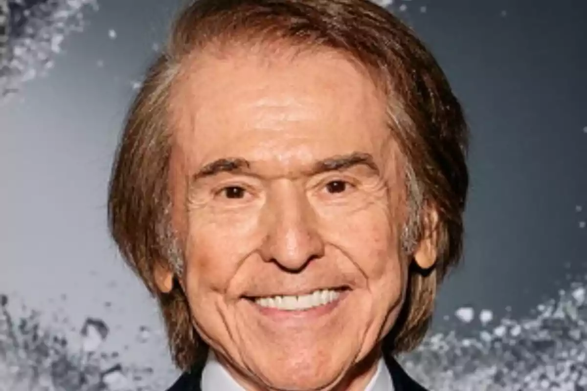 Un hombre mayor sonriendo con el cabello castaño y un fondo oscuro.