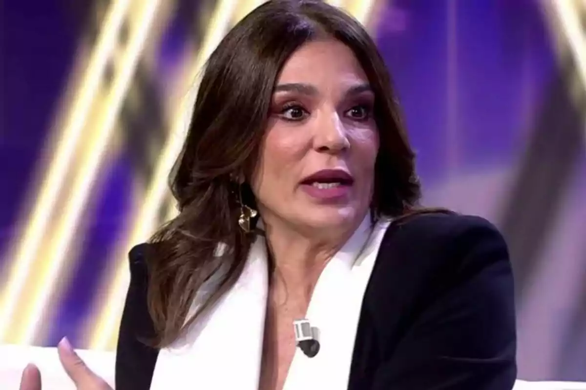 Raquel Bollo con cabello oscuro y chaqueta blanca y negra hablando con fondo iluminado en De Viernes.