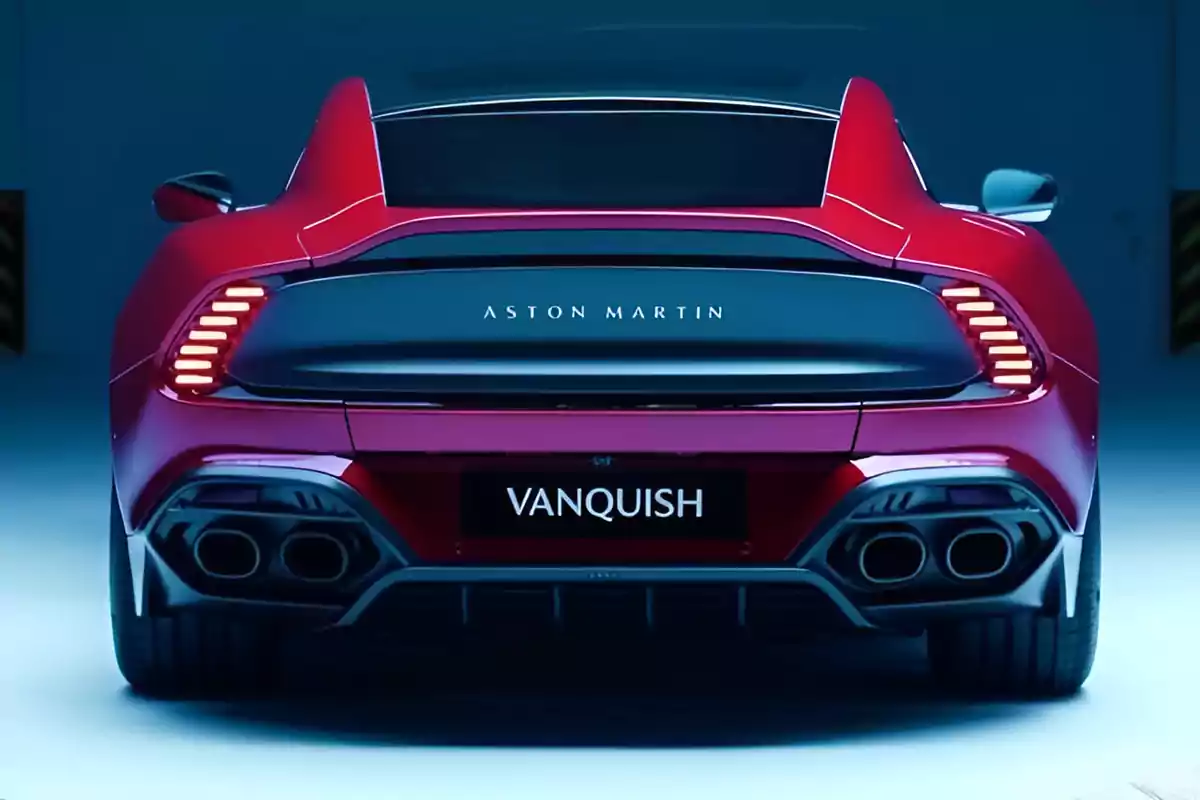 Vista trasera de un coche deportivo Aston Martin Vanquish rojo con luces traseras encendidas.