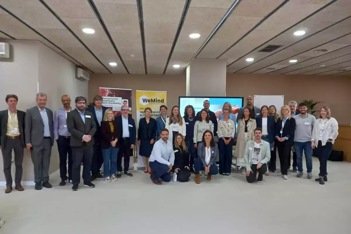 Un grupo de personas posando juntas en un salón de conferencias con carteles de fondo y ambiente profesional