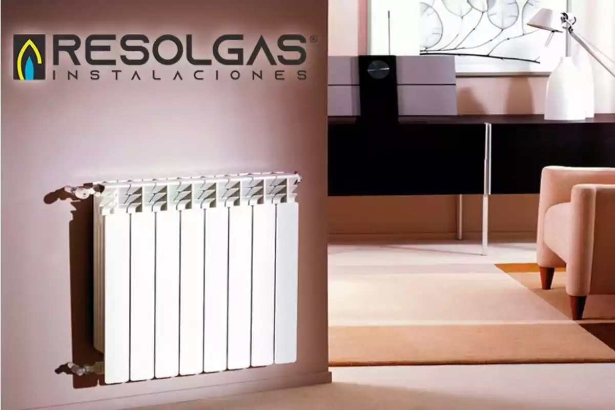 Radiador blanco en una sala moderna con logotipo de Resolgas Instalaciones en la pared.