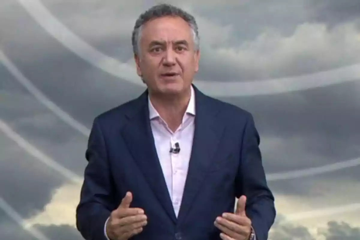 Plano medio de Roberto Brasero vestido con un traje azul y camisa clara hablando frente a un fondo de nubes grises. Plano medio de Roberto Brasero vestido con un traje azul y camisa clara hablando frente a un fondo de nubes grises.