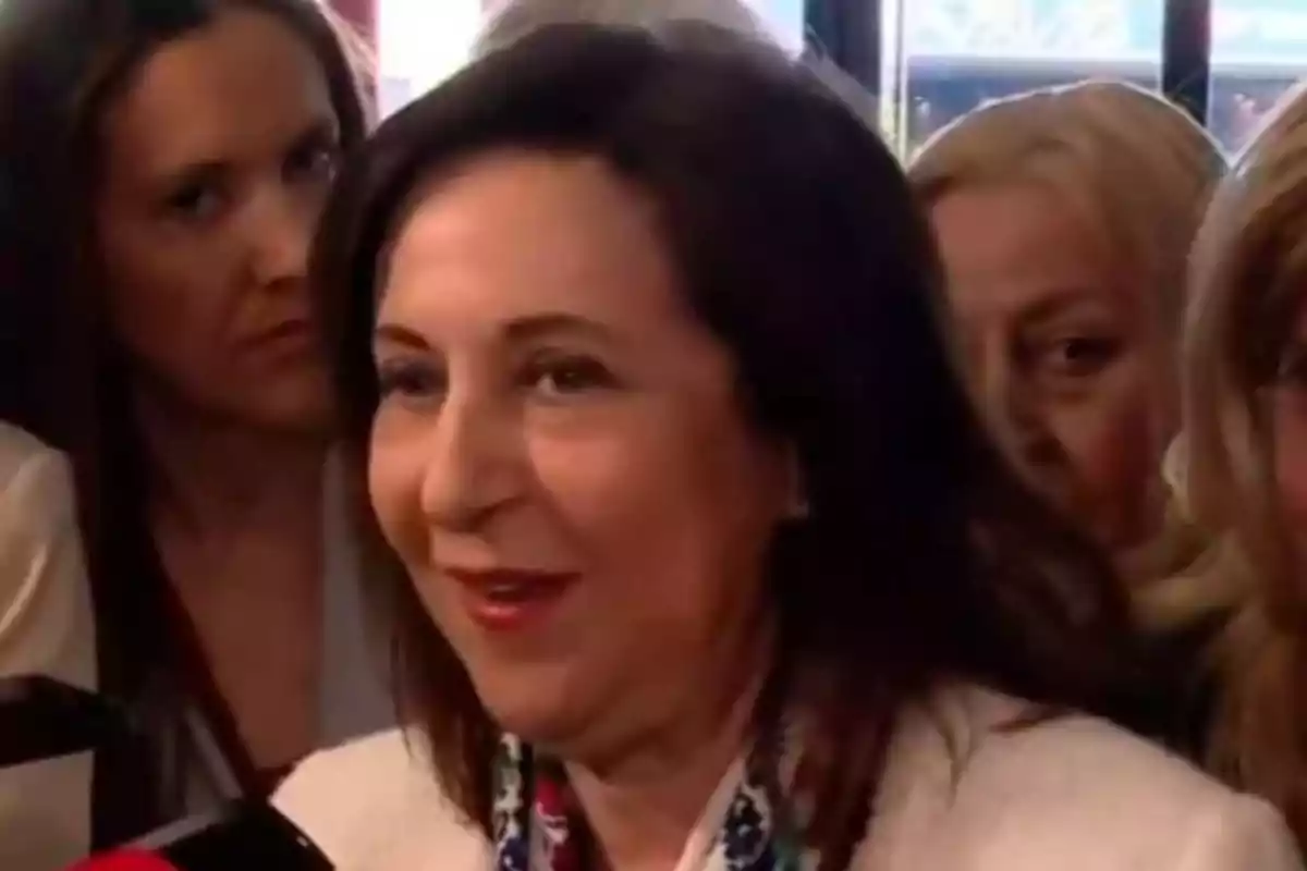 Una mujer sonriente rodeada de otras personas en un evento. Una mujer sonriente rodeada de otras personas en un evento.