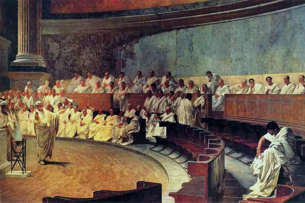 Una pintura que representa a un grupo de hombres vestidos con togas blancas en un foro romano, con uno de ellos de pie hablando apasionadamente mientras los demás lo observan desde sus asientos en un semicírculo.