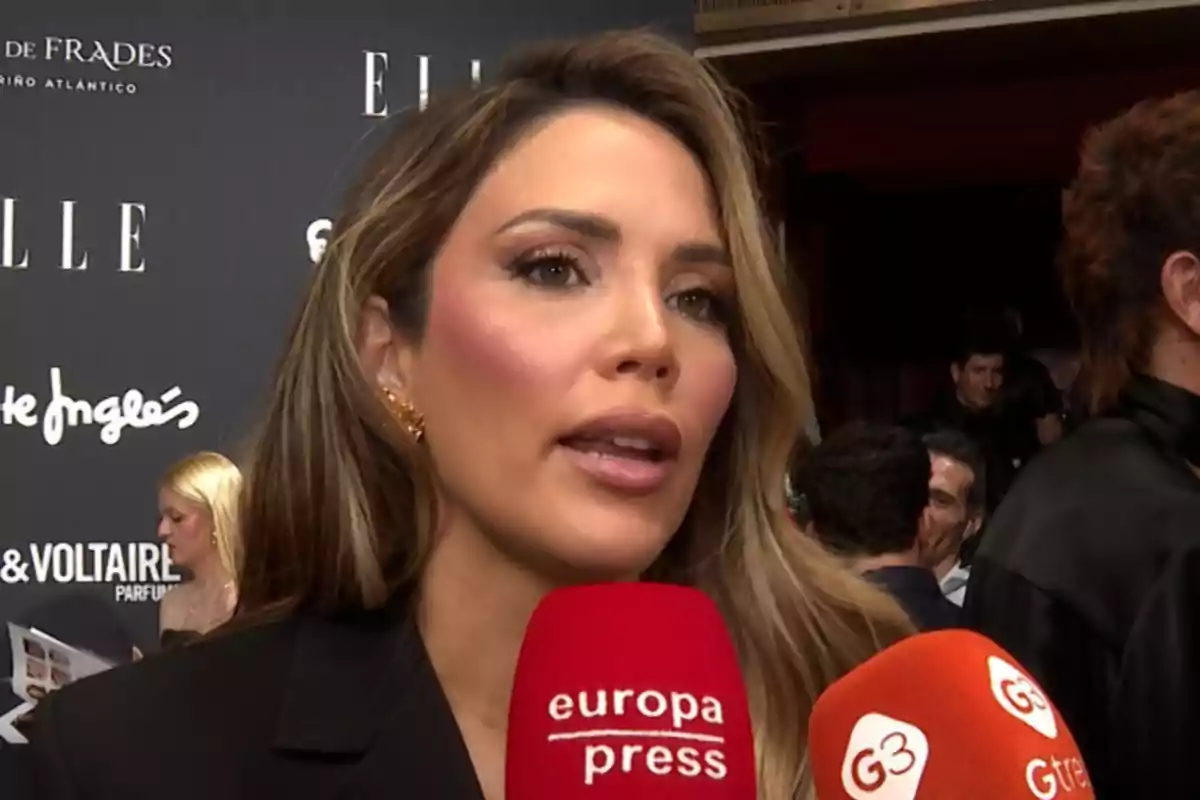 Rosanna Zanetti siendo entrevistada en un evento con fondo de logotipos y micrófonos rojos frente a ella Rosanna Zanetti siendo entrevistada en un evento con fondo de logotipos y micrófonos rojos frente a ella