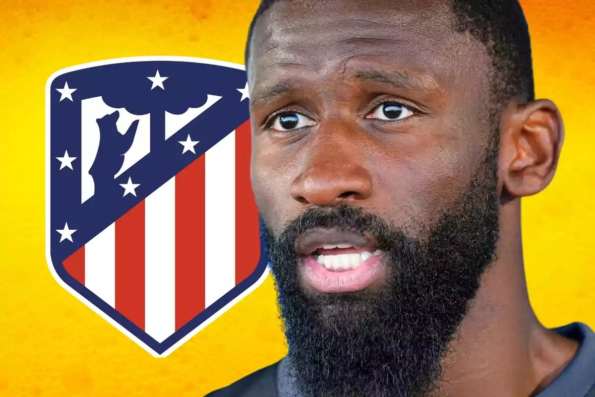 Hombre con barba frente al escudo del Atlético de Madrid sobre un fondo amarillo.