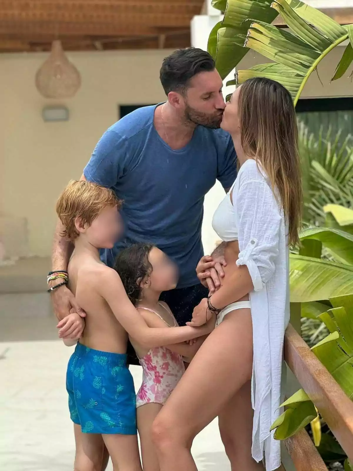 La familia de Rudy Fernández y Helen Lindes abrazándose y besándose en un entorno tropical, con dos niños pequeños y una ella embarazada. La familia de Rudy Fernández y Helen Lindes abrazándose y besándose en un entorno tropical, con dos niños pequeños y una ella embarazada.